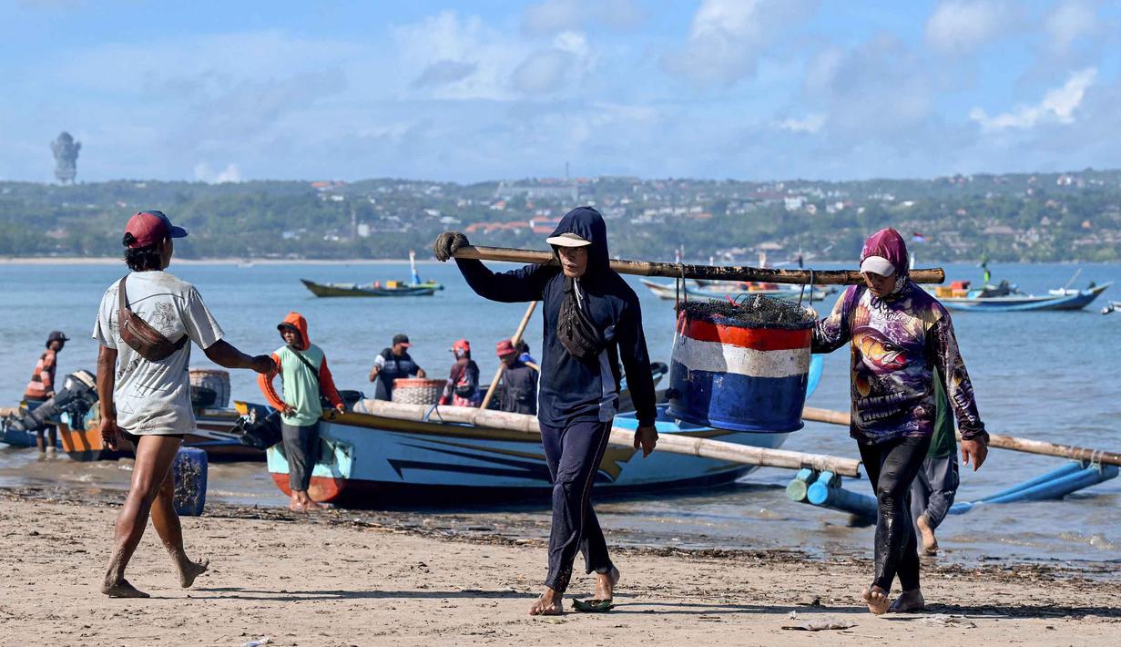 Para pekerja membawa ikan setelah para nelayan menurunkan hasil tangkapan mereka dari perahu di pantai Kedonganan dekat Denpasar, Bali, pada Jumat 10 April 2026. Provinsi Bali memiliki sejumlah pelabuhan yang berperan penting dalam mendukung kegiatan perikanan dan kelautan. (SONNY TUMBELAKA/AFP)