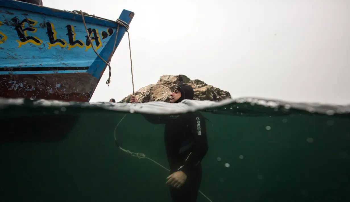 Penyelam bersantai setelah menjelajahi lambung kapal yang karam di Pantai Ancon, dekat Lima, Peru, Minggu (27/3). (AP Photo/Rodrigo Abd)