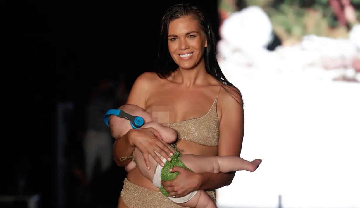 Model Mara Martin berjalan di atas runway sambil menyusui bayinya mengenakan pakaian renang Sports Illustrated pada Miami Swim Week 2018 di Florida, Minggu (15/8). Mara adalah salah satu finalis yang terpilih untuk tampil pada acara itu. (AP/Lynne Sladky)