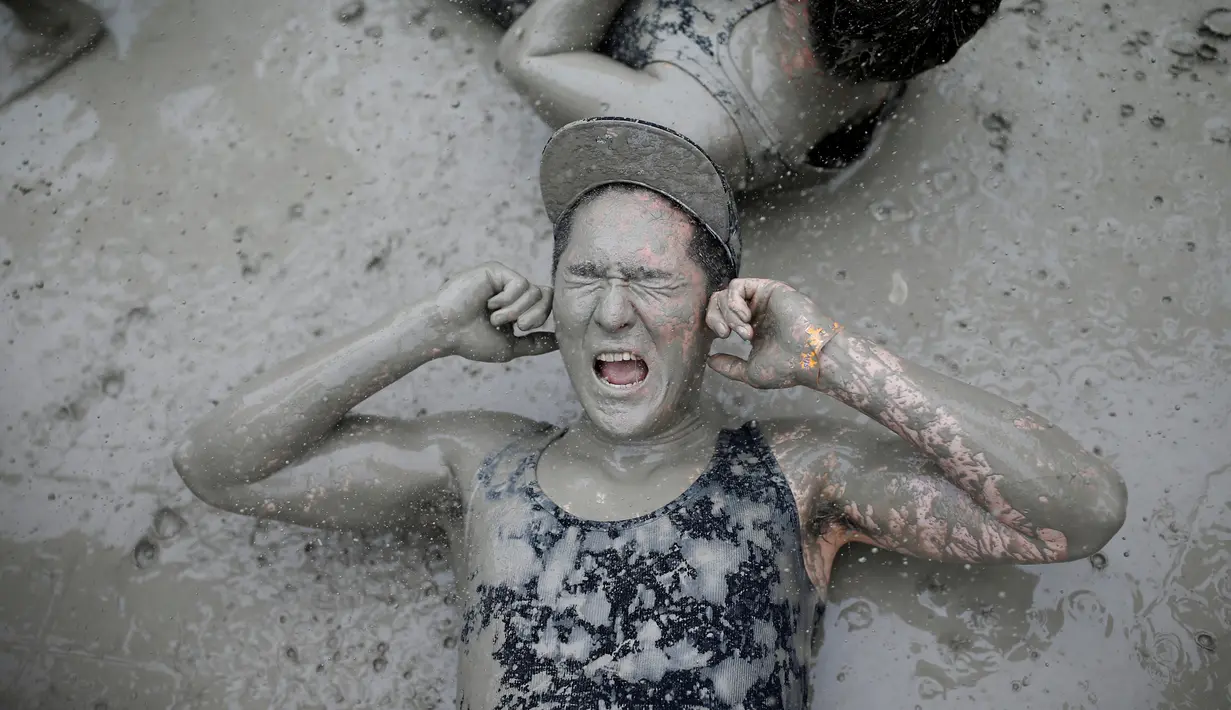Seorang pria menutup mata dan telinganya saat mengikuti permainan dalam Festival lumpur Boryeong di pantai Daecheon, Boryeong, Korea Selatan, (15/7). ( REUTERS/Kim Hong-Ji)