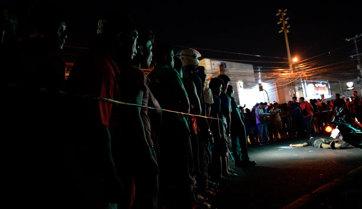 Gambar yang diambil pada 27 Oktober 2016 menunjukkan sejumlah orang berkumpul untuk melihat jasad yang diduga pengedar narkoba tergeletak tewas ditembak oleh orang tak dikenal di Manila, Filipina. (AFP PHOTO/Noel CELIS)