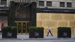 Seorang perempuan melewati Saks Fifth Avenue yang dipasangi papan pelindung di Fifth Avenue di New York, Amerika Serikat pada 1 November 2020. Langkah itu dilakukan saat para peretail berupaya melindungi properti dari penjarahan atau kerusuhan lainnya dalam beberapa hari mendatang (Xinhua/Wang Ying)
