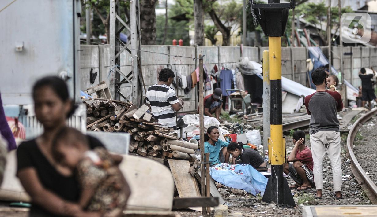 Sejumlah tunawisma beraktivitas di dekat gubuknya yang berada di bantaran rel kereta api kawasan Senen, Jakarta, Minggu (14/2/2021). Aminah (58), salah seorang tunawisma mengaku terpaksa tinggal di pinggir rel akibat tak mampu menyewa rumah kontrakan. (merdeka.com/Iqbal S. Nugroho)