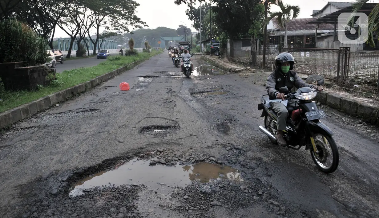 Pengendara motor melintasi jalan rusak dan berlubang di Jalan Tegar Beriman, Cibinong, Bogor, Minggu (31/5/2020). Sudah berbulan-bulan akses yang dikenal sebagai jalan Pemda Cibinong ini sangat memprihatinkan hingga sering menyebabkan kecelakaan terlebih saat musim hujan. (merdeka.com/Iqbal Nugroho)