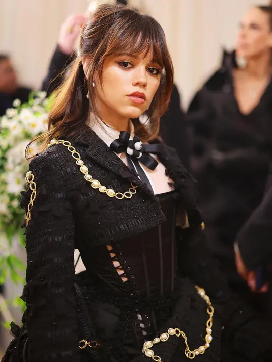 Jenna Ortega tampil memesona dengan rambut half-done dan poni. Winged liner dan lipstik nude pink melengkapi penampilan flawless-nya [@thombrowne]