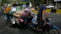 Seorang pedagang mengendarai kereta motornya yang berisi sayuran untuk dijual karena pasar tetap ditutup di tengah pembatasan lockdown yang diberlakukan untuk mencoba menghentikan lonjakan kasus virus corona COVID-19 di Phnom Penh, Kamboja, Selasa (11/5/2021). (TANG CHHIN Sothy/AFP)