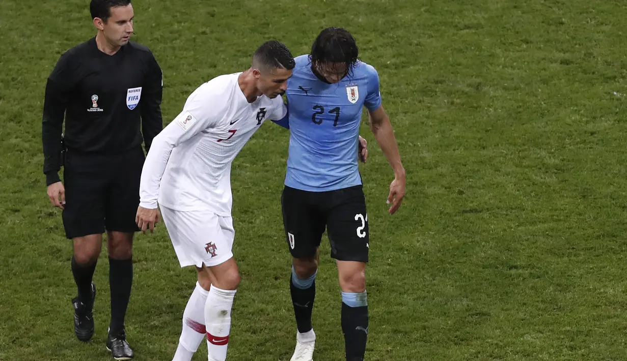 Ronaldo membantu Edinson Cavani keluar dari lapangan pada laga 16 besar Piala Dunia 2018 di Fisht Stadium, Sochi, Rusia, (30/6/2018). Portugal kalah 1-2 dari Uruguay. (AP/Darko Vojinovic)