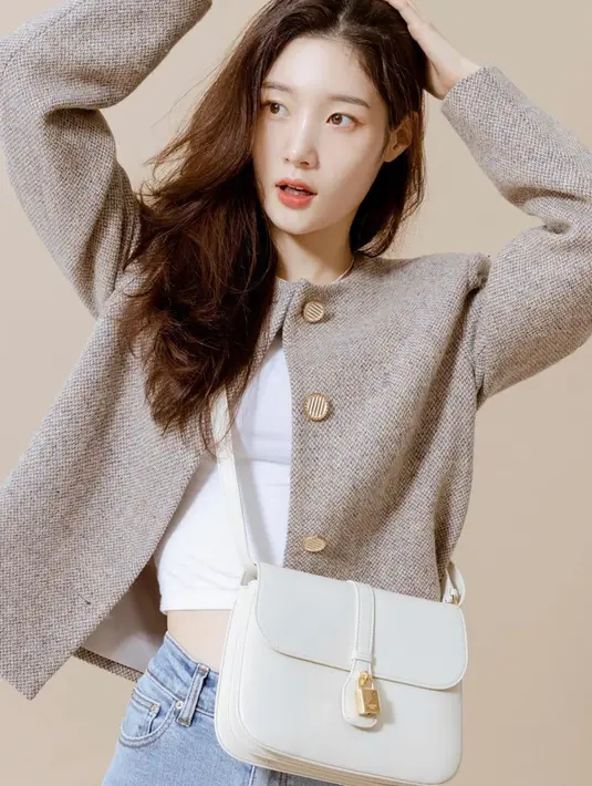 Jung Chae Yeon juga menghadirkan tampilan kasual dengan sweater cokelat muda, kaus putih di dalamnya, dan celana jeans, yang disempurnakan dengan tas Celine berwarna putih. Foto: Document/Celine.
