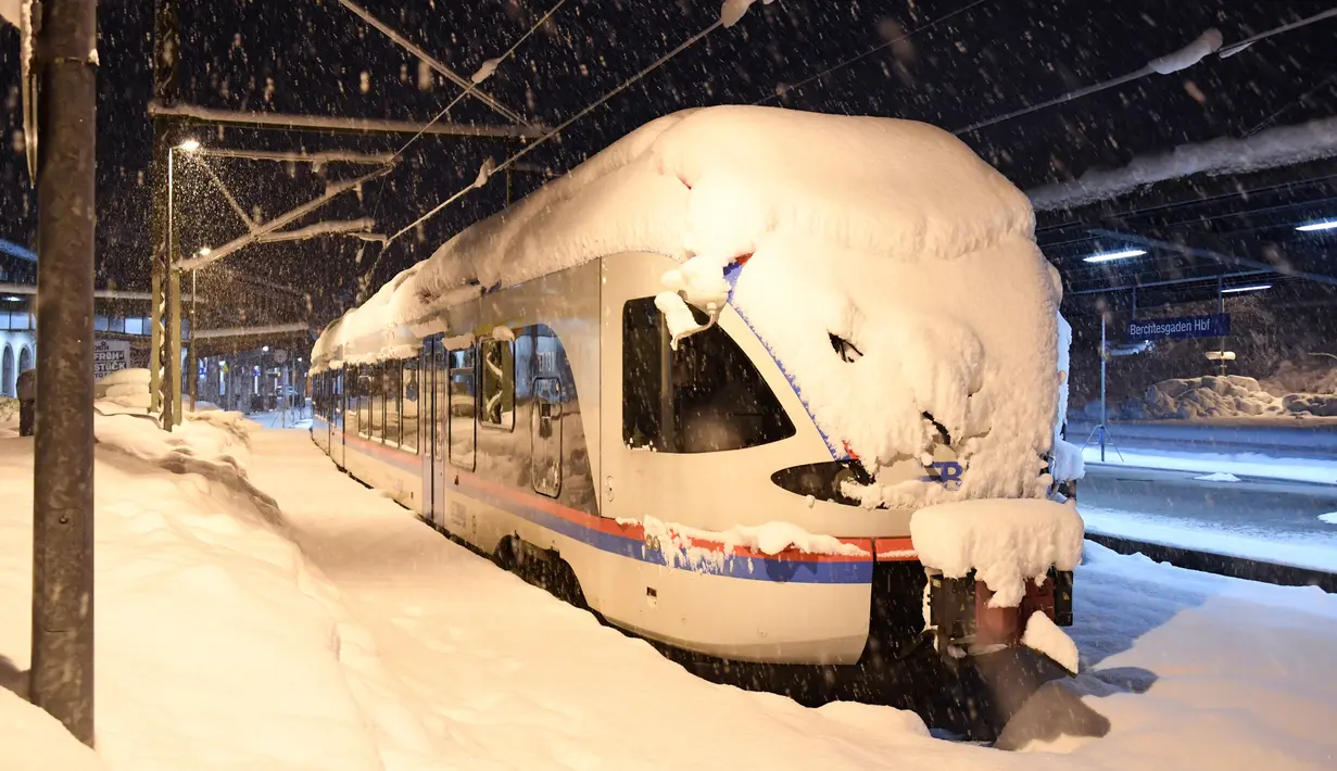 Sebuah kereta komuter tertutup salju di Stasiun Berchtesgaden, Jerman, Kamis (10/1). Transportasi kereta api berhenti karena hujan salju lebat. (Tobias Hase/dpa/AFP)