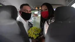Ayrton (kiri) dan Natasha dengan mengenakan masker berpose setelah pernikahan drive-thru mereka di kantor pencatatan sipil di Santa Cruz, Rio de Janeiro, Brasil, 28 Mei 2020. Fasilitas ini untuk memudahkan pasangan yang ingin mengesahkan hubungan saat pandemi covid-19. (AP/Silvia Izquierdo)
