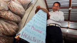 Miguel Andagana menunjukkan poster pemberantas puntung rokok di rumahnya Puerto Ayora, di Kepulauan Galapagos (9/10). Andagana ingin diakui oleh Guinness Records sebagai orang yang memberantas puntung rokok dari Puerto Ayora. (REUTERS/Guillermo Granja)