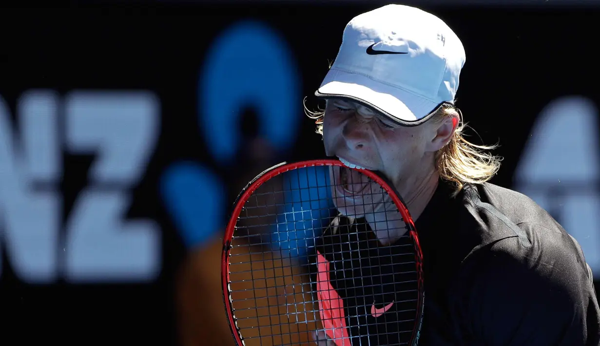 Petenis Kanada Denis Shapovalov menggigit raketnya dengan frustrasi saat pertandingan putaran kedua melawan petenis Prancis Jo-Wilfried Tsonga di kejuaraan tenis Australia Terbuka di Melbourne, Australia, (17/1). (AP Photo / Dita Alangkara)