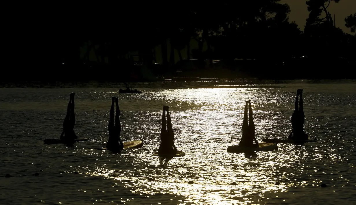 Sejumlah wanita mengenakan bikini saat melakukan gerakan yoga Float Metta dengan papan seluncur di Laut Adriatic, Kroasia, Kamis (6/8/2015). (REUTERS/Pawel Kopczynski)
