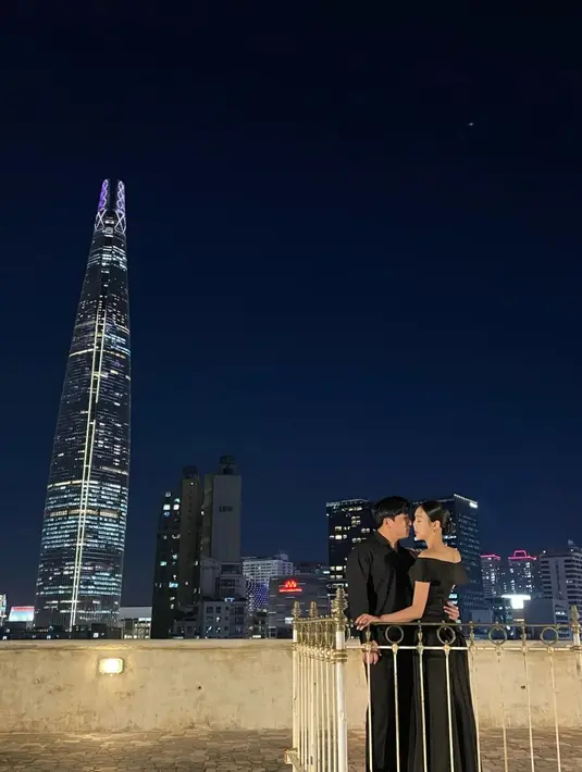 Kompak memakai outfit warna hitam, Choi Hanbit tampak dirangkul mesra oleh calon suami di bawah langit malam. [Foto: IG/choi_tea_il].