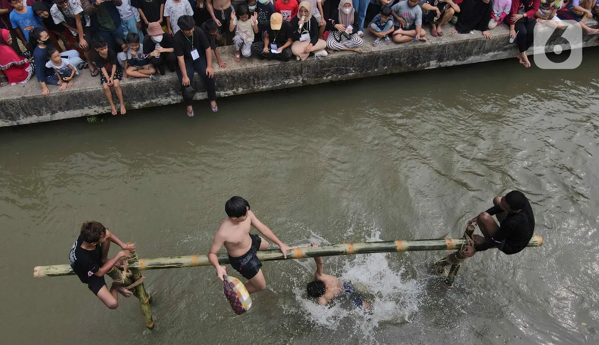 Peserta saling menjatuhkan pada lomba pukul bantal di aliran Kalimalang, Jakarta Timur, Sabtu (27/8/2022). Perlombaan di Kalimalang yang diselenggarakan kembali setelah dua tahun berhenti akibat pandemi covid-19 ini untuk memeriahkan peringatan HUT ke-77 Kemerdekaan RI. (Liputan6.com/Herman Zakharia)