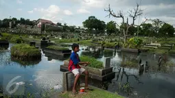 Seorang anak bermain layang-layang diatas makam di Tempat Pemakaman Umum (TPU) Tanah Kusir, Jakarta, Selasa (25/4). (Liputan6.com/Gempur M. Surya)