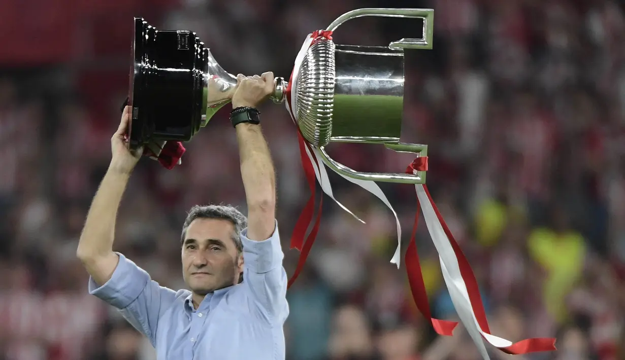 Pelatih Athletic Bilbao, Ernesto Valverde, mengangkat trofi setelah menjuarai Copa del Rey di Stadion Olimpico de Sevilla, Minggu (7/4/2024). (AFP/Cristina Quicler)