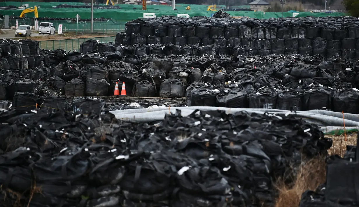 Foto ini diambil pada 29 Februari 2020 menunjukkan tanah permukaan yang terkontaminasi radiasi yang dikemas dalam tas hitam di sebuah lapangan di Tomioka, prefektur Fukushima di sebelah utara PLTN Daiichi Daiichi Fukushima yang rusak parah akibat gempa dan tsunami 2011. (AFP/Charly Triballeau)