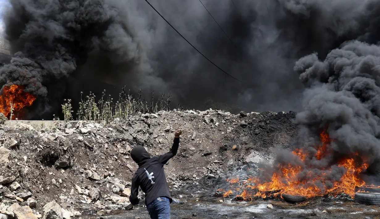 <p>Seorang pengunjuk rasa Palestina melemparkan batu ke pasukan keamanan Israel di tengah bentrokan menyusul demonstrasi menentang perampasan tanah Israel di Desa Kfar Qaddum dekat pemukiman Yahudi Kedumim, Tepi Barat, 6 Mei 2022. (JAAFAR ASHTIYEH/AFP)</p>