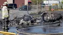 Petugas pemadam mengamati puing pesawat kecil yang jatuh di dekat Bandara Teterboro di luar Kota New York, Senin (15/5). Pesawat itu langsung terbakar setelah menabrak sebuah gedung di komplek bisnis. (Aristide Economopoulos/NJ Advance Media via AP)