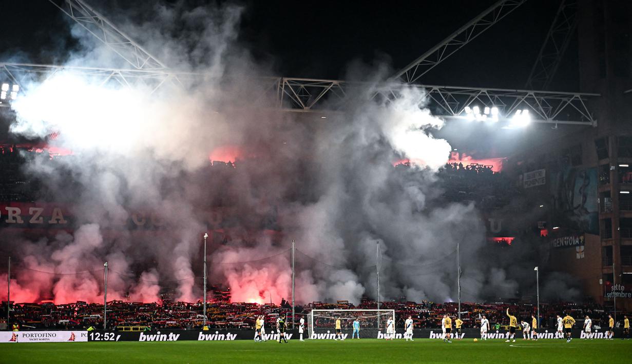 Suporter Genoa menyalakan suar saat pertandingan melawan Inter Milan pada laga lanjutan Liga Italia 2023/2024 di Stadion Luigi Ferraris, Genoa, Italia, Sabtu (30/12/2023) dini hari WIB. (AFP/Piero Cruciatti)