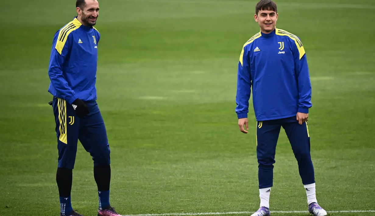 Bek Juventus, Giorgio Chiellini (kiri) dan penyerang Paulo Dybala tersenyum saat ambil bagian dalam sesi latihan di tempat latihan Continassa di Turin, Italia (15/3/2022). Pada leg pertama Juventus bermain imbang dengan Villarreal 2-2. (AFP/Marco Bertorello)