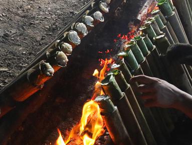 Pekerja membakar lemang di kawasan Kwitang, Jakarta, Minggu (9/3/2025). (Liputan6.com/Herman Zakharia)
