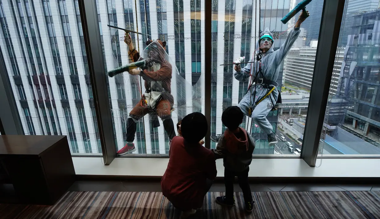 Dua petugas sedang membersihkan kaca jendela  sebuah hotel sambil mengenakan kostum babi hutan dan tikus di Tokyo, Kamis (19/12/2019). Hal ini mereka lakukan untuk merayakan bahun baru Imlek 2019 di Tahun Babi Tanah dan menyambut Tahun Tikus pada 2020. (AP Photo/Eugene Hoshiko)