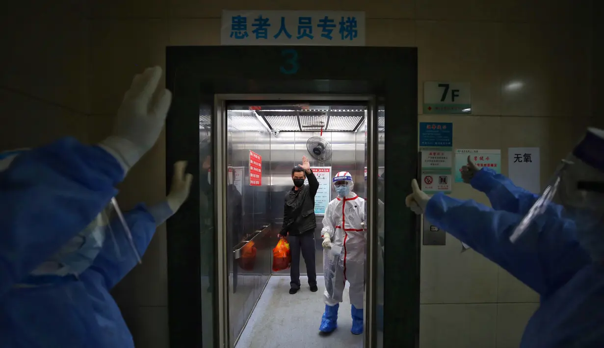 Petugas medis melambaikan tangan kepada pasien yang terjangkit virus corona COVID-19 di Rumah Sakit Palang Merah di Wuhan, Provinsi Hubei, China, 16 Maret 2020. Kasus baru pasien terinfeksi virus corona COVID-19 di negara yang menjadi pusat penyebaran pandemi ini mulai menurun.  (Photo by STR/AFP)
