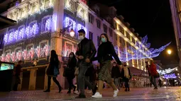 Sejumlah warga yang mengenakan masker berjalan di bawah lampu-lampu Natal dan Tahun Baru pada masa pandemi COVID-19 di Kota Lisbon, Portugal, 17 Desember 2020. Portugal akan memberlakukan aturan jam malam mulai pukul 23.00 pada Malam Tahun Baru. (Xinhua/Pedro Fiuza)