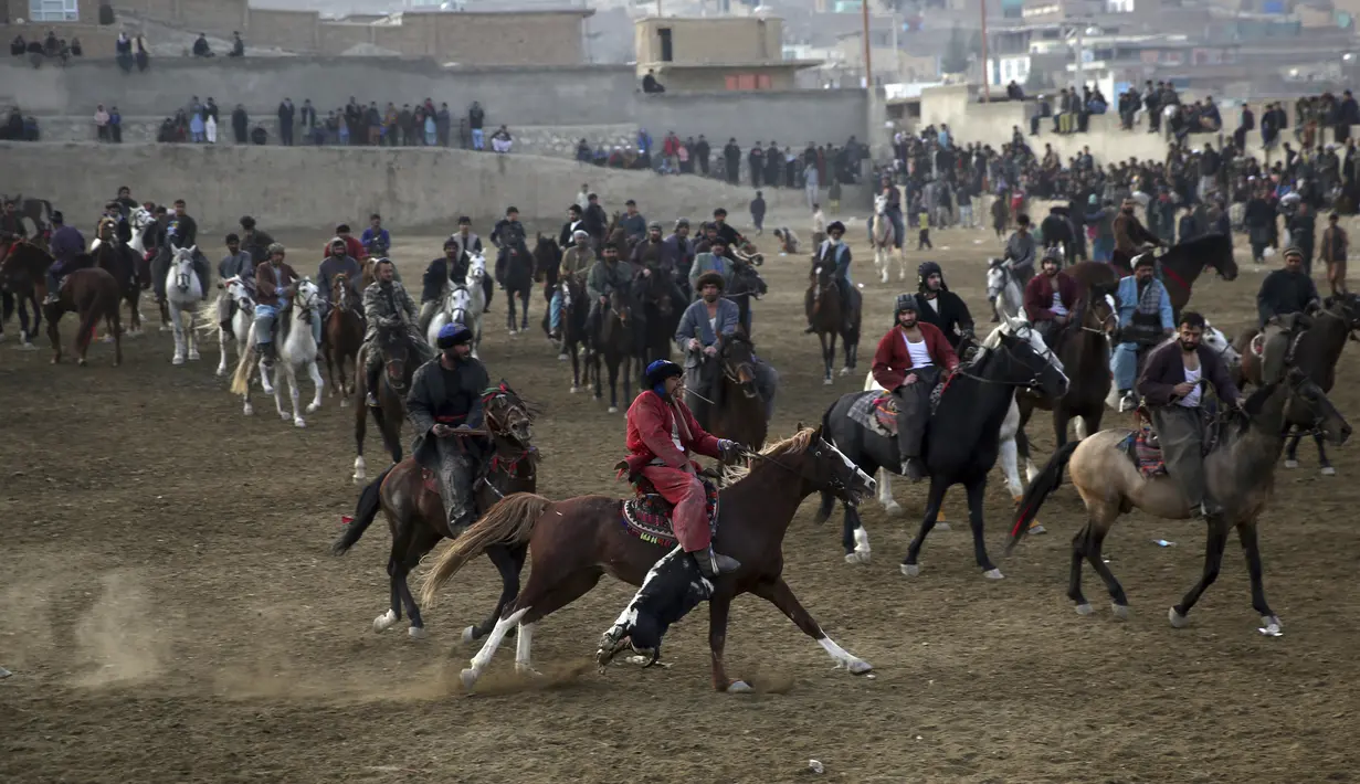 Penunggang kuda berebut kambing pada pertandingan persahabatan buzkashi di pinggiran Kabul, Afghanistan, Jumat (27/12/2019). Buzkashi adalah olahraga tradisional Afghanistan di mana para pemainnya berlomba untuk menempatkan bangkai kambing ke dalam lingkaran. (AP Photo/Rahmat Gul)