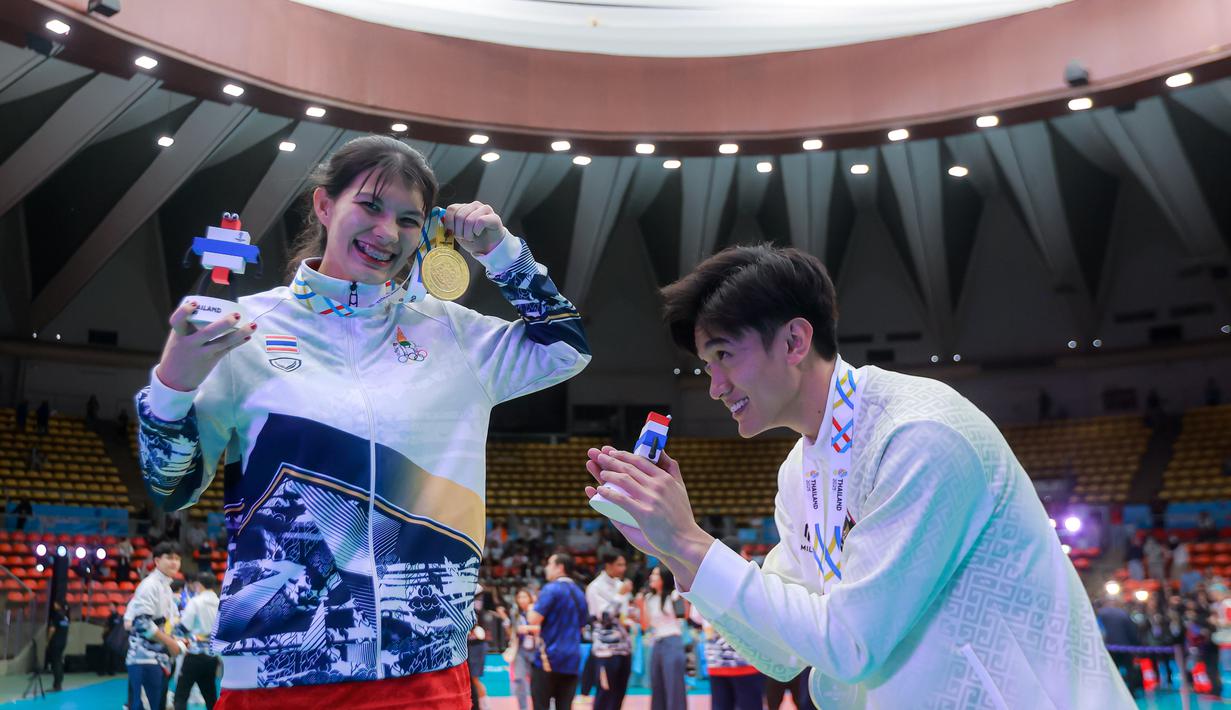 Keduanya saling merayakan kemenangan bersama. Alfin Daniel Pratama dengan medali peraknya. Sementara, McEntee Catherine dengan medali emasnya. Tampak dalam foto, pevoli Indonesia Alfin Daniel Pratama (kanan) menunduk saat bersama dengan kekasihnya yang juga penerjemah Timnas voli putra Thailand, McEntee Catherine, di di Stadion Indoor Hua Mak, Jumat (19/12/2025). (Bola.com/Bagaskara Lazuardi)