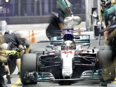 Pebalap Mercedes, Lewis Hamilton menanti perbaikan mobilnya oleh mekanik saat berada di pit lane pada sesi latihan bebas F1 GP Singapura, Marina Bay City Circuit, (15/9/2017). (AP/Wong Maye-E)