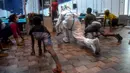 Seorang dokter yang mengenakan setelan Alat Pelindung Diri memberikan instruksi kepada pasien saat melakukan yoga di dalam bangsal di kompleks olahraga Commonwealth Games (CWG) Village yang sementara diubah menjadi pusat perawatan Covid-19 di New Delhi, India, Kamis (16/7/2020). (Money SHARMA / AFP)