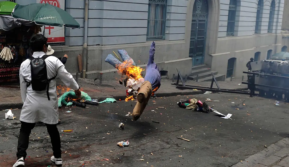 Seorang mahasiswa kedokteran membakar boneka saat demonstrasi di dekat lapangan Murilo di La Paz, Bolivia (19/12). Para mahasiswa memprotes undang-undang baru Presiden Evo Morales terkait sanksi pidana malapraktik medis. (AFP Photo/Jorge Bernal)
