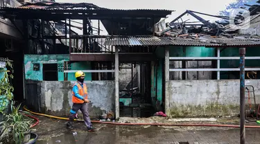 Petugas pemadam kebakaran melintas di depan salah satu rumah warga yang terbakar di Jalan Masjid Alhuda atau depan Stasiun Kebayoran Lama RT 05/01, Jakarta Selatan, Selasa (24/5/2022). Petugas pun mengerahkan 27 unit mobil pemadam kebakaran dari Sudin Damkar Jakarta Selatan ke lokasi kejadian. (Liputan6.com/Johan Tallo)