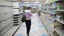 Seorang perempuan melihat-lihat barang apa saja yang tersisa di dekat rak kosong di toko Rite Aid yang akan ditutup Senin depan di Alhambra, California, Rabu (18/10/2023). (Frederic J. BROWN / AFP)