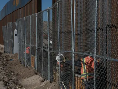 Pekerja menyelesaikan pembangunan tembok yang memisahkan AS dengan Meksiko, Rabu (25/1). Rencananya Trump Wall atau Tembok Trump akan dibangun di perbatasan AS dan Meksiko sepanjang 3.200 kilometer. (AP PHOTO)