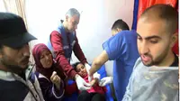 Petugas medis Palestina merawat seorang gadis terluka akibat pemboman Israel di sebuah gedung pusat pelatihan kejuruan UNRWA yang digunakan para pengungsi tempat berlindung di Khan Younis, Jalur Gaza selatan, 24 Januari 2024. (AP)