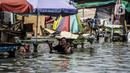 Seorang wanita menggendong anak kecil melintasi banjir rob di kawasan Muara Angke, Jakarta, Selasa (9/11/2021). Badan Penanggulangan Bencana Daerah (BPBD) DKI Jakarta memperkirakan puncak musim hujan dan potensi rob di Ibu Kota terjadi pada Januari hingga Februari 2022. (Liputan6.com/Faizal Fanani)