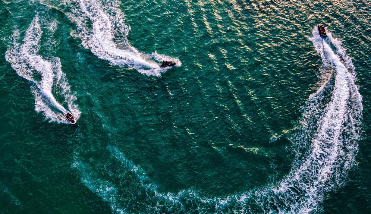 Pantai yang berdekatan dengan kawasan wisata Lampuuk ini menawarkan aktivitas olahraga air, termasuk berenang dan menyelam. Tampak dalam foto, pemandangan udara menunjukkan orang-orang saat berkumpul menikmati masa libur panjang Idulfitri di area olahraga air, Pantai Lhoknga, Aceh, pada Kamis 26 Maret 2026. (Chaideer MAHYUDDIN/AFP)