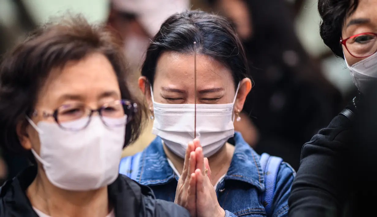 <p>Seorang wanita berdoa sambil memegang dupa setelah kebaktian untuk merayakan ulang tahun Buddha di Kuil Jogye, Seoul, Korea Selatan, Minggu (8/5/2022). (ANTHONY WALLACE/AFP)</p>
