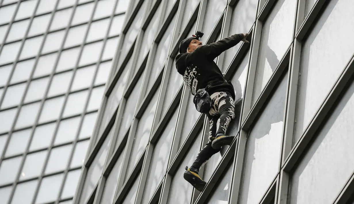 Pendaki Alain Robert atau French Spiderman memanjat Menara Total di kawasan bisnis La Defense, Paris, Prancis, Senin (13/1/2020). Alain hanya bermodalkan tangan kosong, sepasang sepatu panjat, dan sekantong kapur bubuk untuk membersihkan keringat. (Thomas SAMSON/AFP)