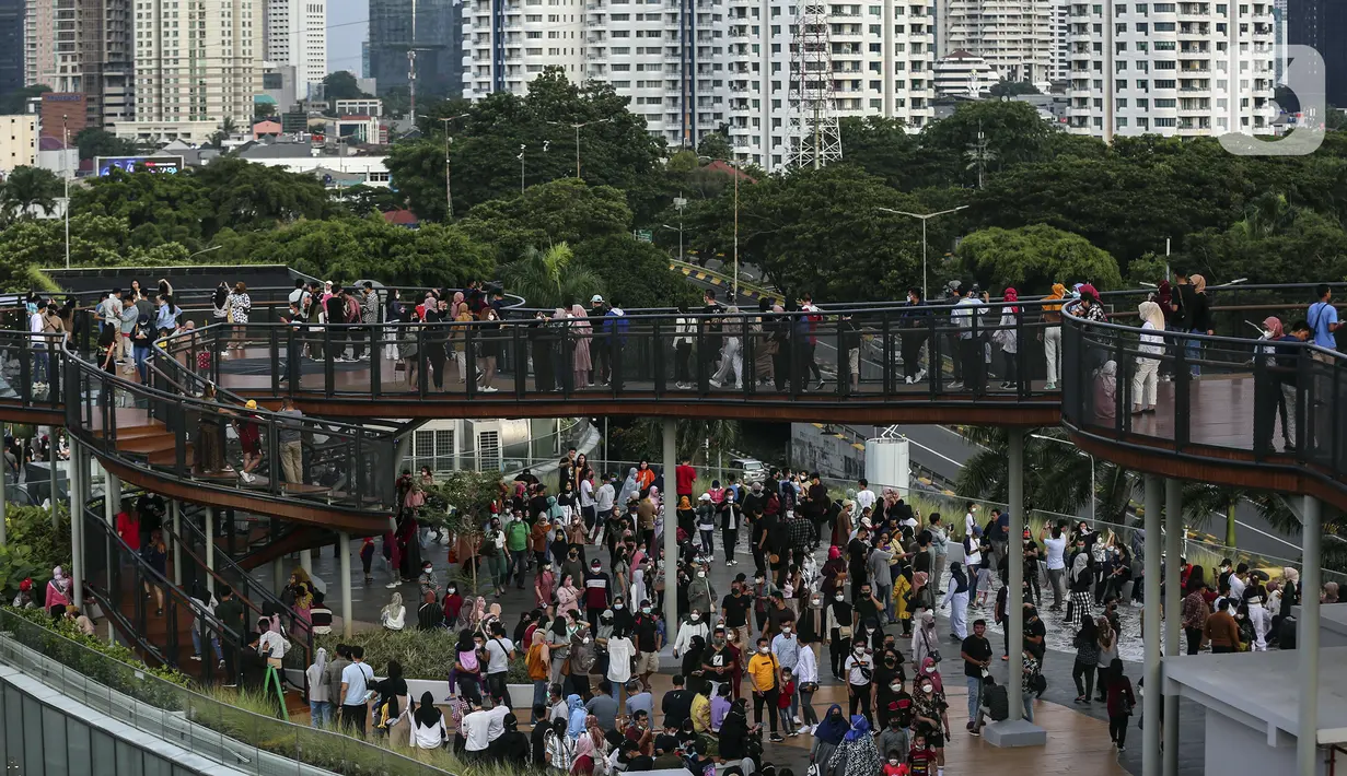 Warga memenuhi Skywalk Senayan Park untuk mengisi libur Tahun Baru dengan menikmati pemandangan Kota Jakarta, Sabtu (1/1/2022). Skywalk Senayan Park kini menjadi salah satu tempat wisata pilihan warga Jakarta lantaran pemandangannya yang instagramable. (Liputan6.com/Johan Tallo)