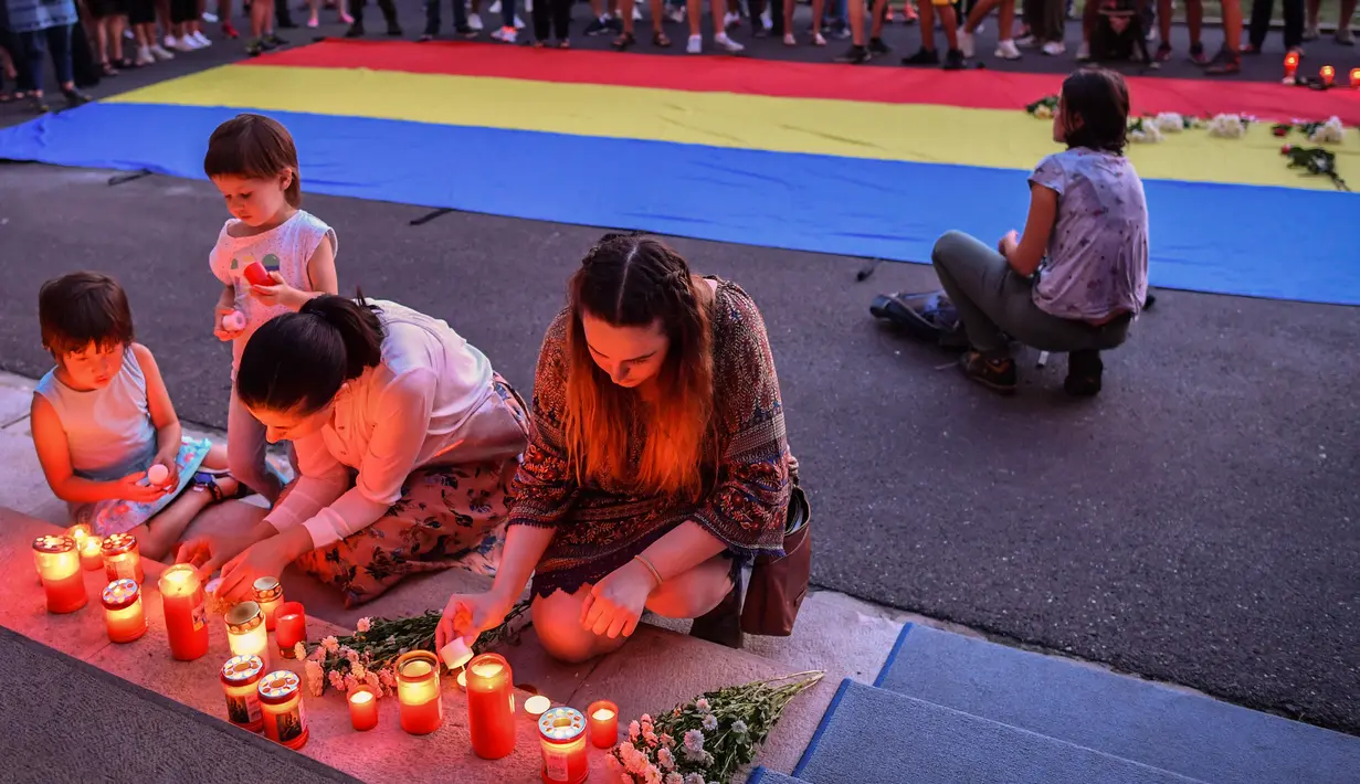 Warga menyalakan lilin untuk memperingati gadis berusia 15 tahun Alexandra yang terbunuh di depan Kementerian Dalam Negeri Rumania di Bucharest (27/7/2019). Alexandra  sempat memberikan petunjuk kepada polisi tentang tempat ia ditahan pengemudi mobil yang menjemputnya. (AFP Photo/Daniel Mihailescu)