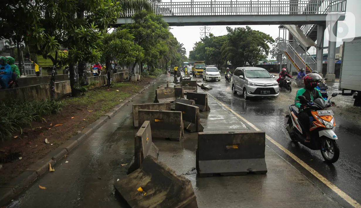 Kendaraan melintas dekat separator busway yang berserakan pascabanjir di Jalan Daan Mogot, Cengkareng, Jakarta, Jumat (3/1/2020). Separator busway tersebut berantakan akibat banjir yang menerjang sejak kemarin. (Liputan6.com/Faizal Fanani)