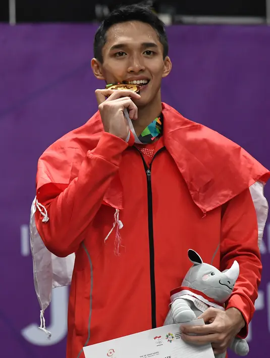 Pebulu tangkis Indonesia, Jonatan Christie mengigit medali emas usai upacara penghargaan cabang olahraga badminton Asian Games 2018 di Jakarta, Selasa (28/8). Jonatan menang atas wakil Chinese Taipei, Chou Tienchen.  (AFP Photo/Sonny Tumbelaka)