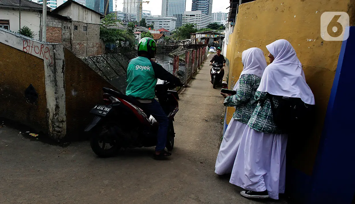 Pengendara sepeda motor melintasi jalur alternatif saat anak sekolah berjalan di belakang Kompleks Patra Jasa, Jakarta Selatan, Rabu (1/3/2023). Jalur alternatif seperti gang, jalan kecil, maupun jalan tembusan menjadi pilihan bagi pengendara sepeda motor untuk menghindari kemacetan di jalan-jalan protokol Ibu Kota. (Liputan6.com/Johan Tallo)