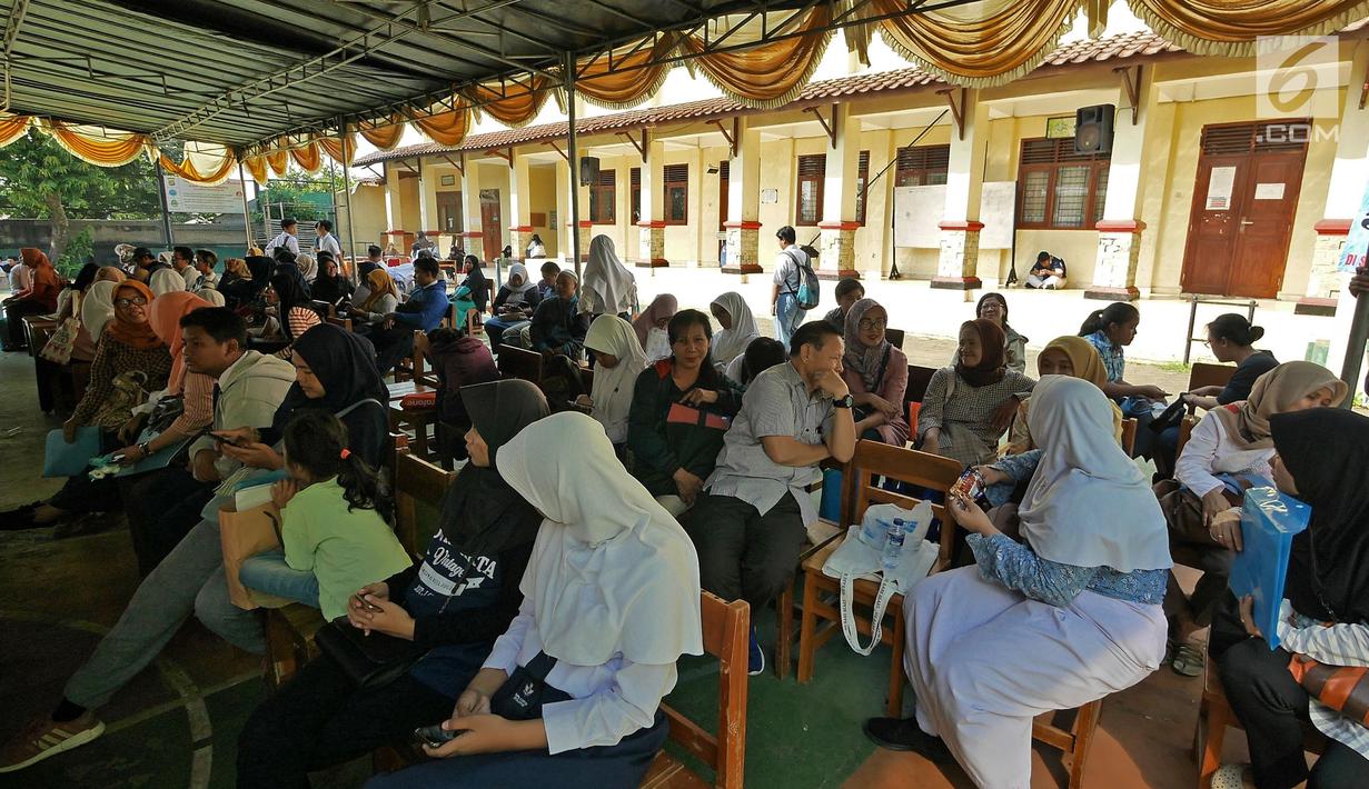 Siswa dan orangtua murid menunggu saat mengikuti seleksi Penerimaan Peserta Didik Baru (PPDB) di SMAN 1 Depok, Kota Depok, Jawa Barat, Selasa (18/6/2019). PPDB SMA dibagi menjadi tiga jalur yakni zonasi, prestasi, dan pemindahan orangtua. (Liputan6.com/Herman Zakharia)