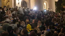 Aparat kepolisian menggunakan semprotan merica untuk membubarkan demonstran di depan parlemen Serbia di Beograd, Selasa (7/7/2020). Ribuan pengunjuk rasa marah setelah pemerintah mengeluarkan keputusan untuk memberlakukan kembali jam malam akibat melonjaknya kasus Covid-19. (AP/Marko Drobnjakovic)